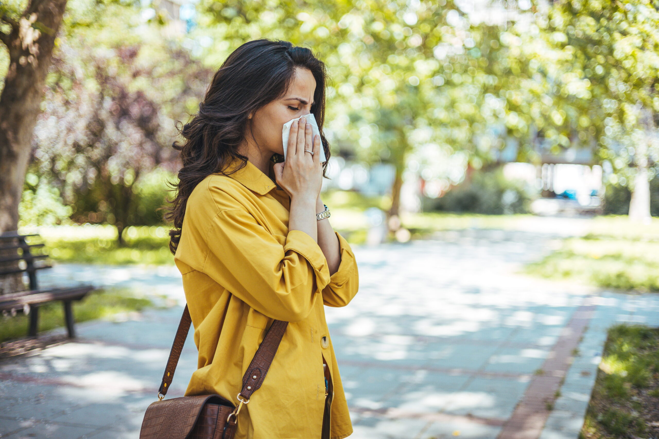 Woman walking with tissue, sneezing from allergies