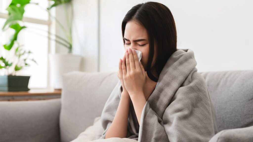 Woman blowing nose with blanket
