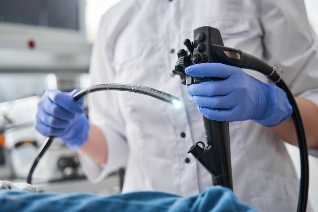 Close up of a doctor wearing gloves and holding an endoscopy tool